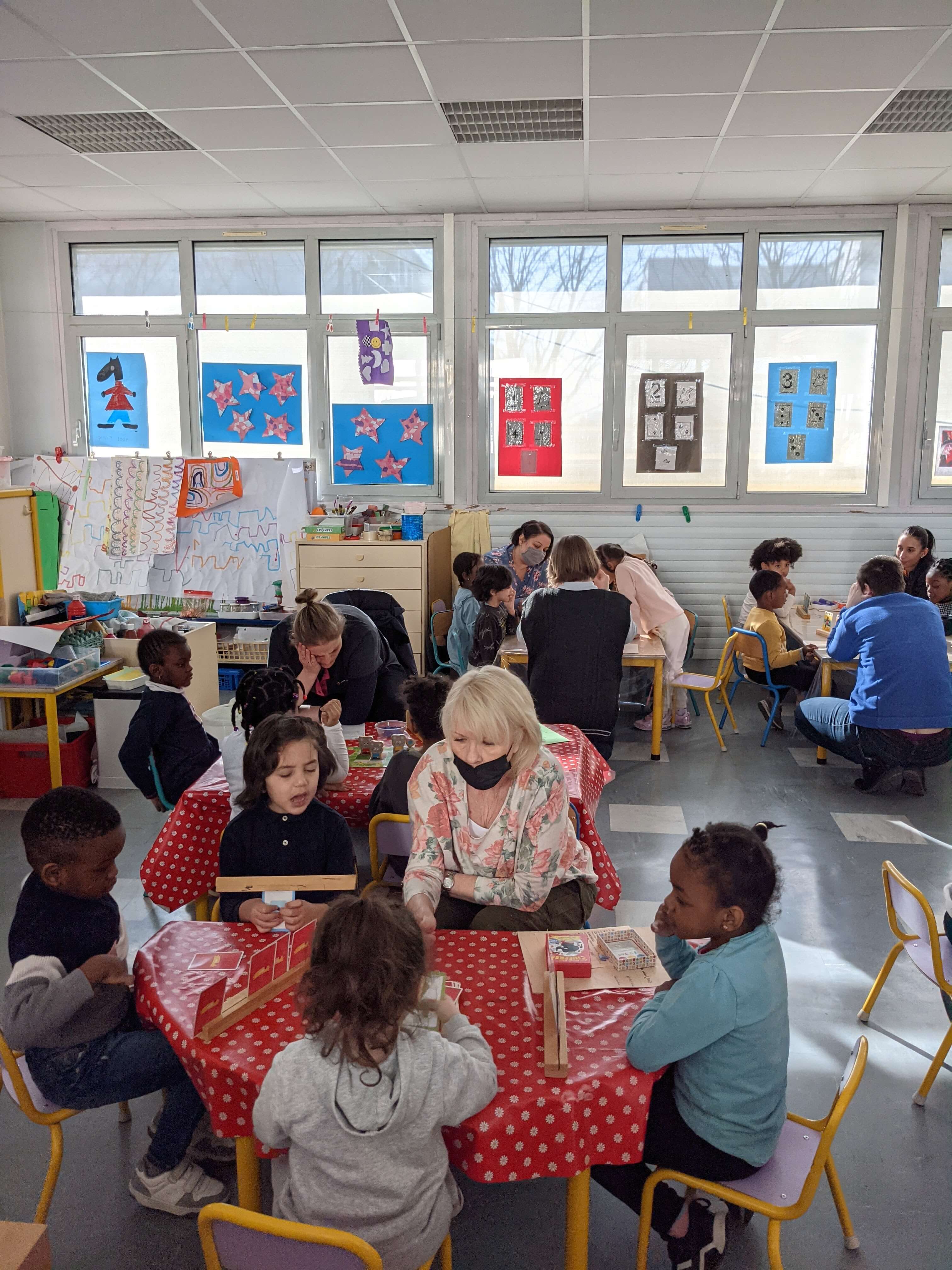 groupe d'enfants jouant à un jeu aidés d'une adulte